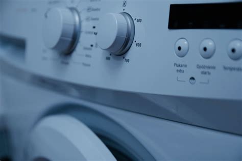 Rankos, valančios skalbimo mašinos filtrą po tekančiu vandeniu