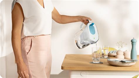 Žmogus pilantis ZeroWater filtruotą vandenį į stiklinę