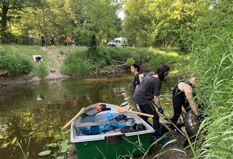 Žmonės, dalyvaujantys upės valymo akcijoje
